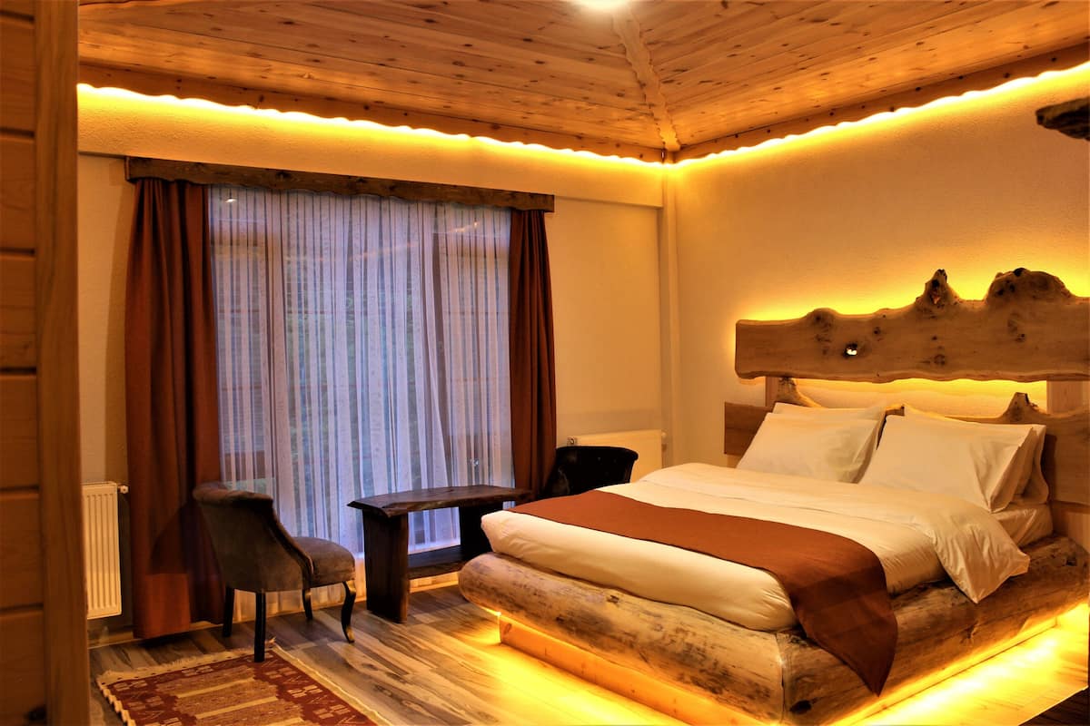 A cozy bedroom with a wooden headboard, a bed with white linens, a small table, and a chair.