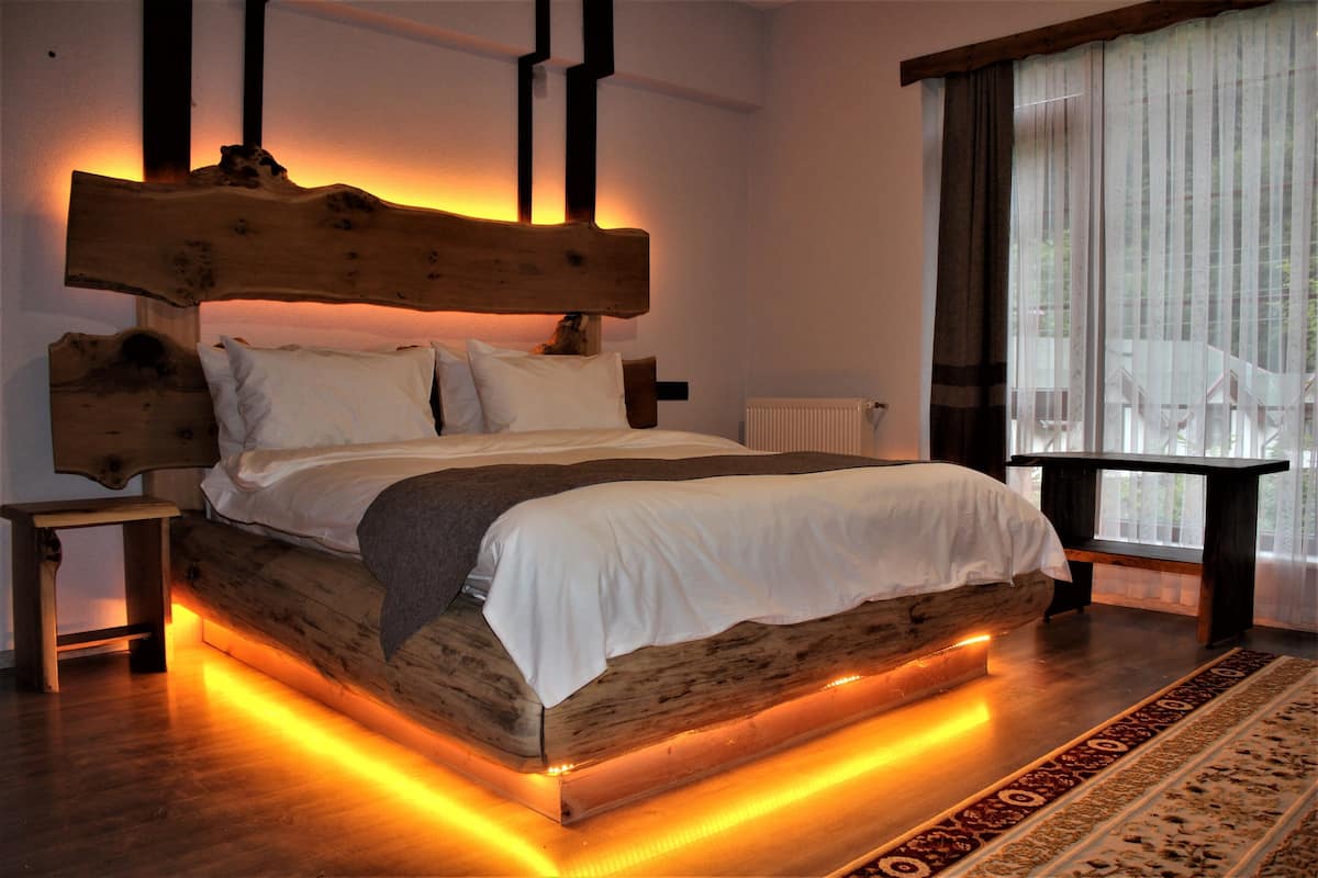 A bed with a wooden headboard, white bedding, and under-bed lighting.