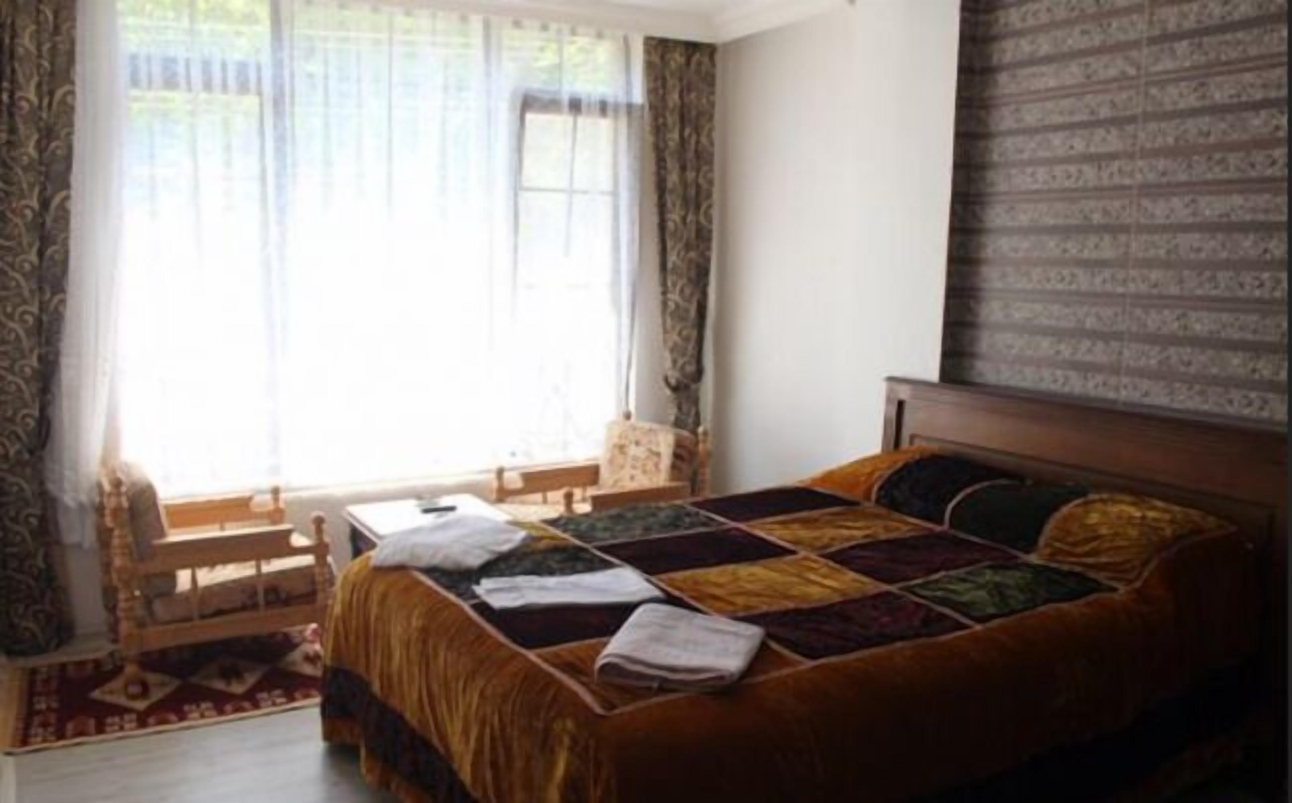 Un dormitorio con una cama grande, un cabecero de madera, una mesita y una silla.