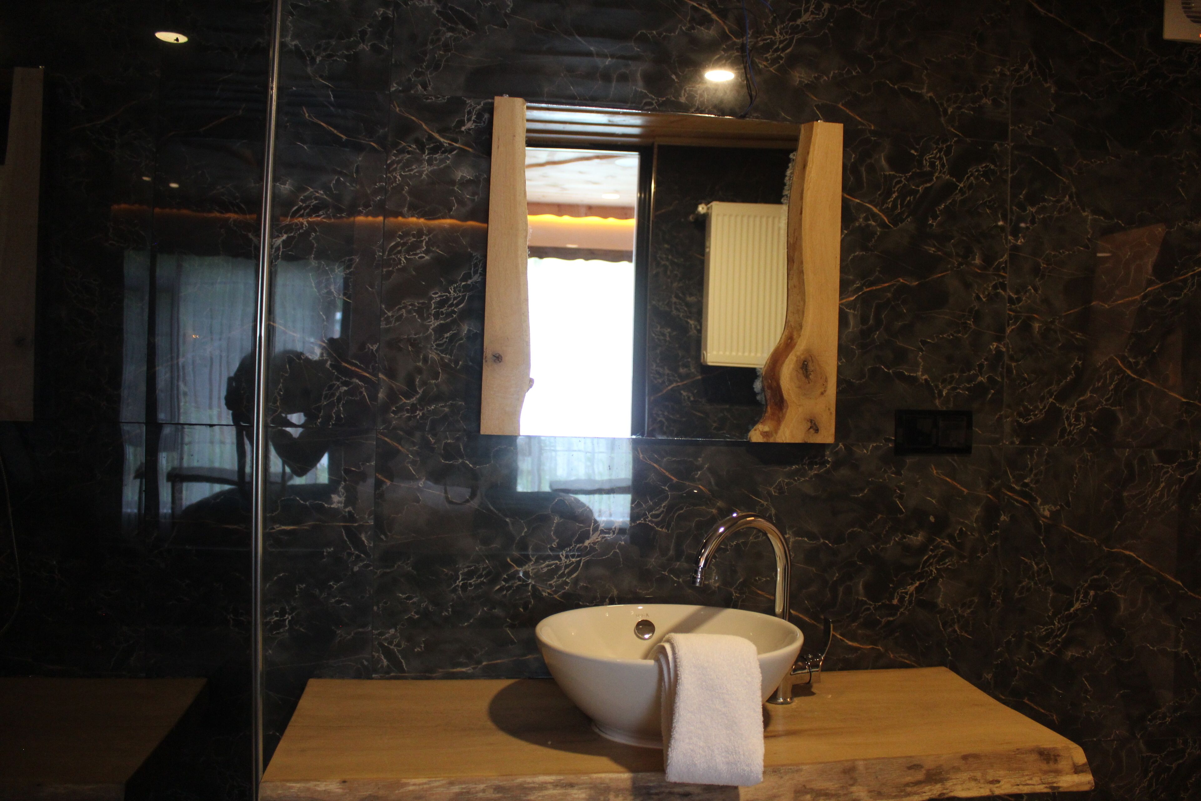 A bathroom with a marble sink, a wooden vanity, and a mirror with a wooden frame.