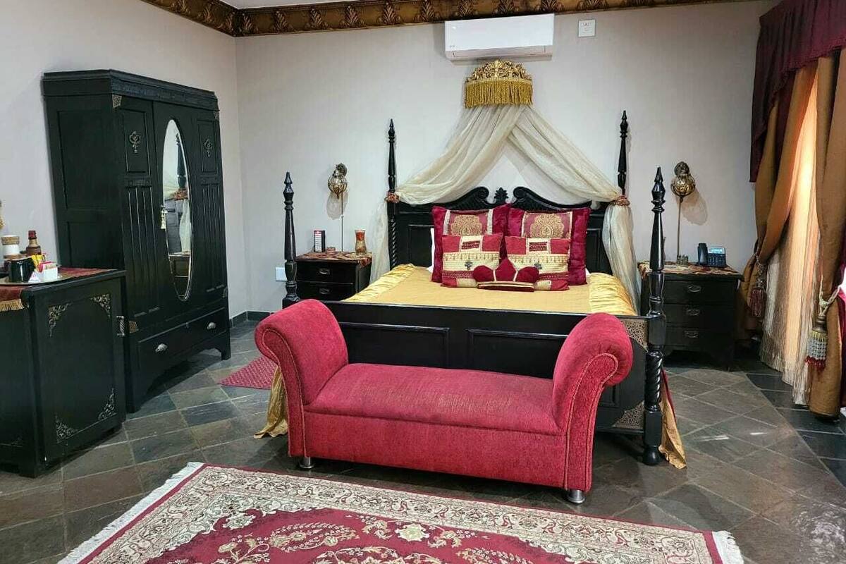 Une chambre à coucher avec un lit, un canapé rouge, une armoire et un baldaquin décoratif.