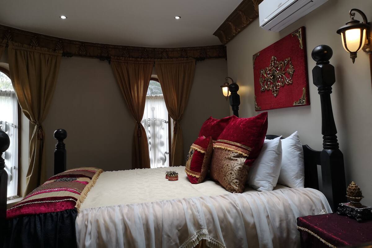 Une chambre à coucher comprenant un lit, des rideaux, un climatiseur fixé au mur et des éléments décoratifs sur les murs.