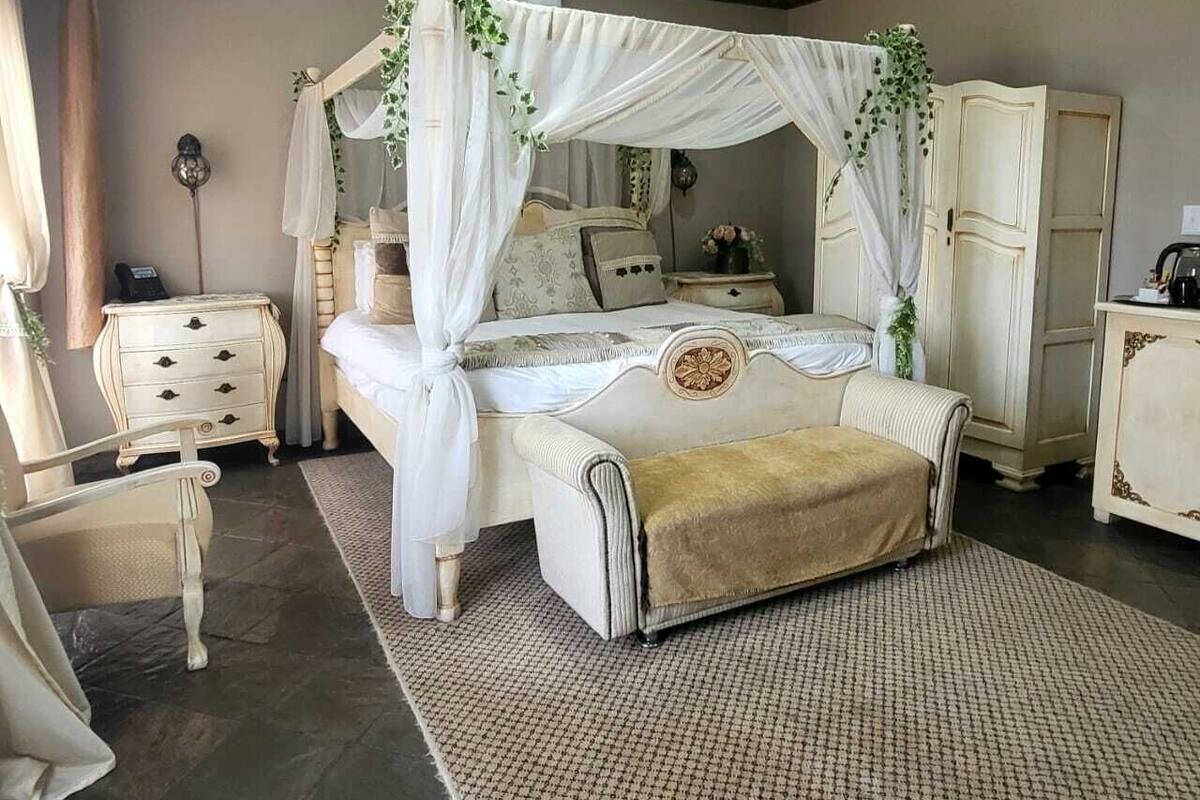 Une chambre à coucher avec un lit à baldaquin, une table de chevet, une commode et une chaise.