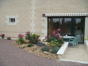 A patio area with a table and chairs, surrounded by a garden with various plants and flowers. - Homerez - House in Mouterre-Silly. (Mouterre-Silly)