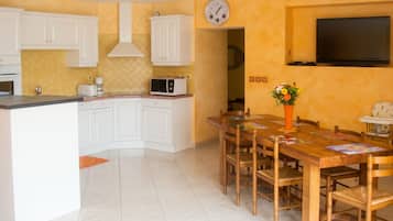 A kitchen with white cabinets, a microwave, and a dining table with chairs.