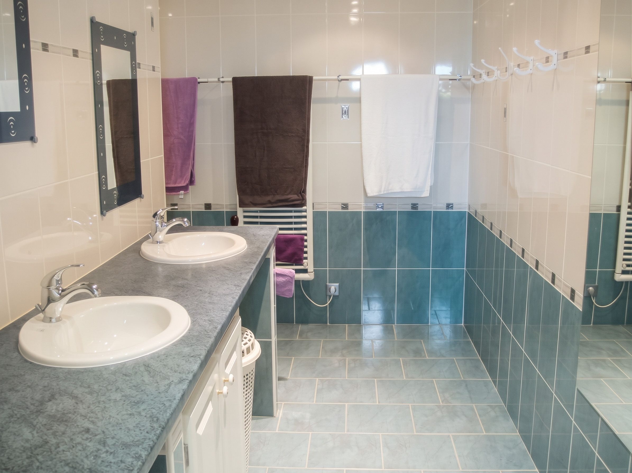 Une salle de bain avec deux lavabos, un miroir et un porte-serviettes.