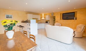 A modern living room with a sofa, a dining table with chairs, and a kitchen area in the background. - Homerez - House in Mouterre-Silly. (Mouterre-Silly)