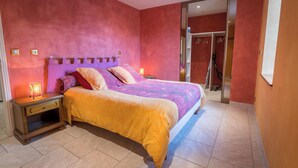 Un dormitorio con cama, mesitas de noche y una puerta corrediza que da a un baño.