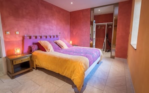 Un dormitorio con cama, mesitas de noche y una puerta corrediza que da a un baño.