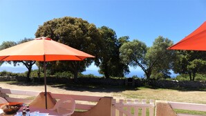 Une terrasse extérieure avec une table et des chaises, une clôture en bois et une vue sur la mer.