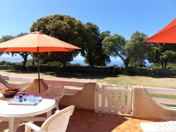 Un patio exterior con mesa y sillas, una cerca de madera y vista al mar.