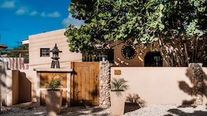 A building with a wooden door, a stone wall, and a number '28' sign. - A private vacation villa with gorgeous pool. (Kralendijk)