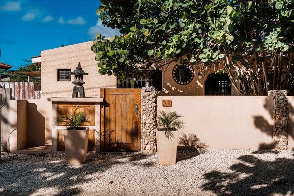 A building with a wooden door, a stone wall, and a number '28' sign. - A private vacation villa with gorgeous pool. (Kralendijk)