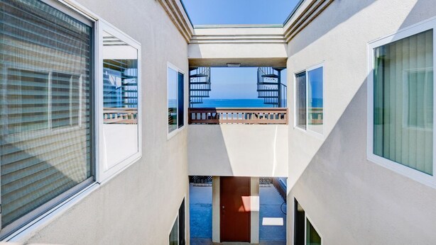 A modern building with a central balcony overlooking a body of water.