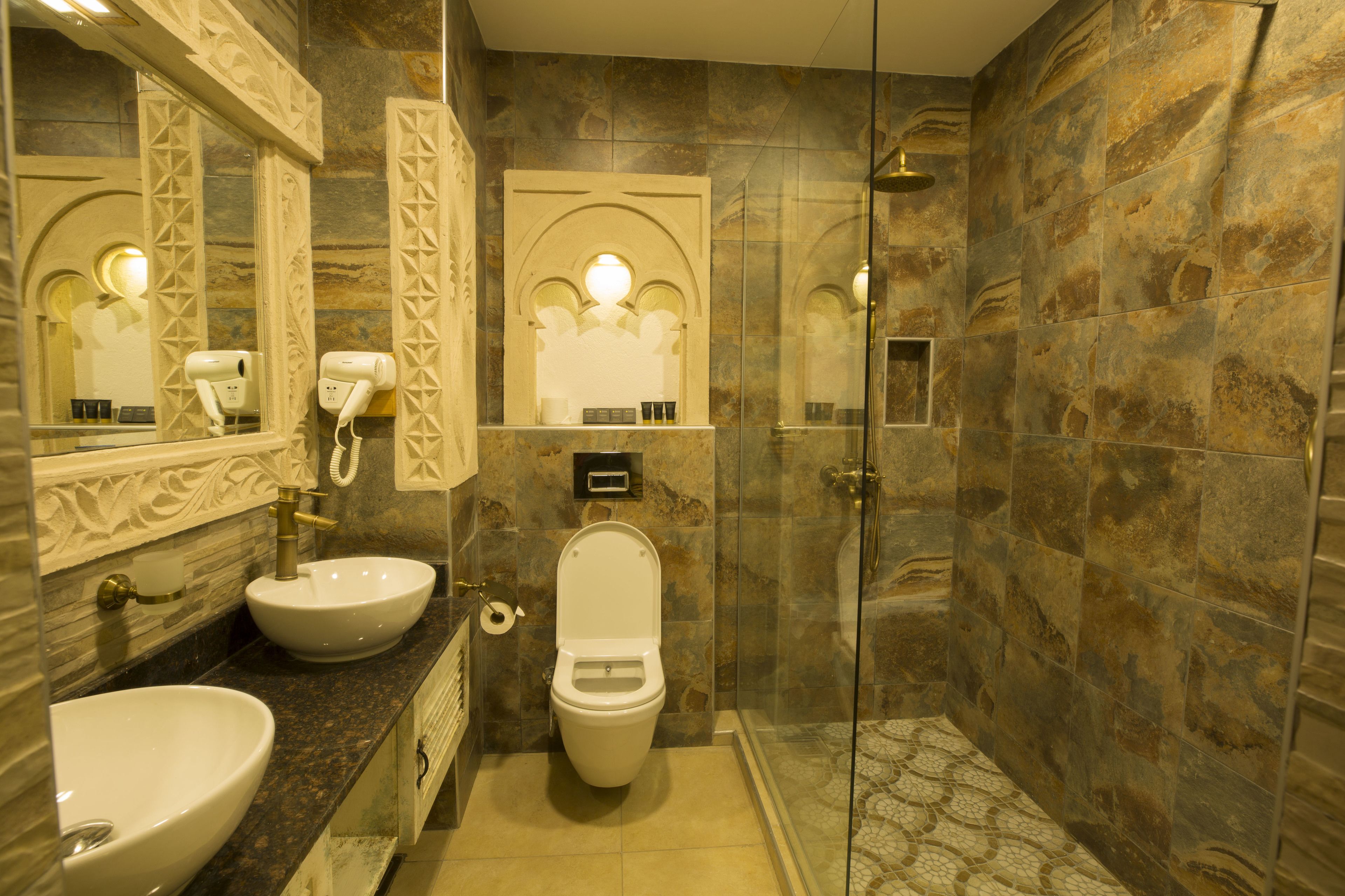 Un baño con lavamanos, inodoro y ducha con mampara de vidrio.