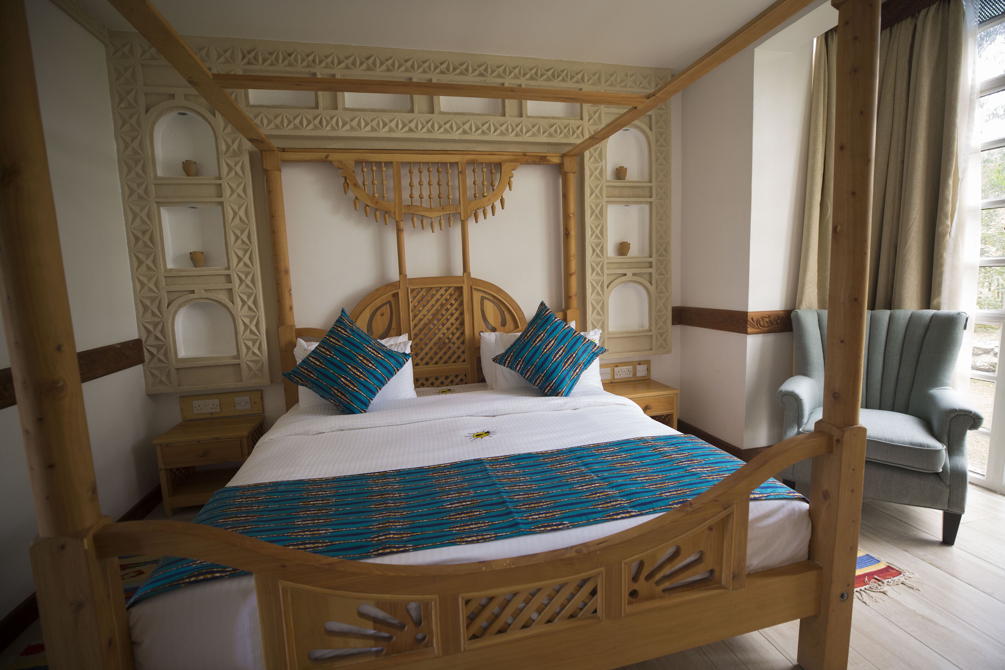 A four-poster bed with a wooden frame, two pillows, and a blue and orange bedspread.