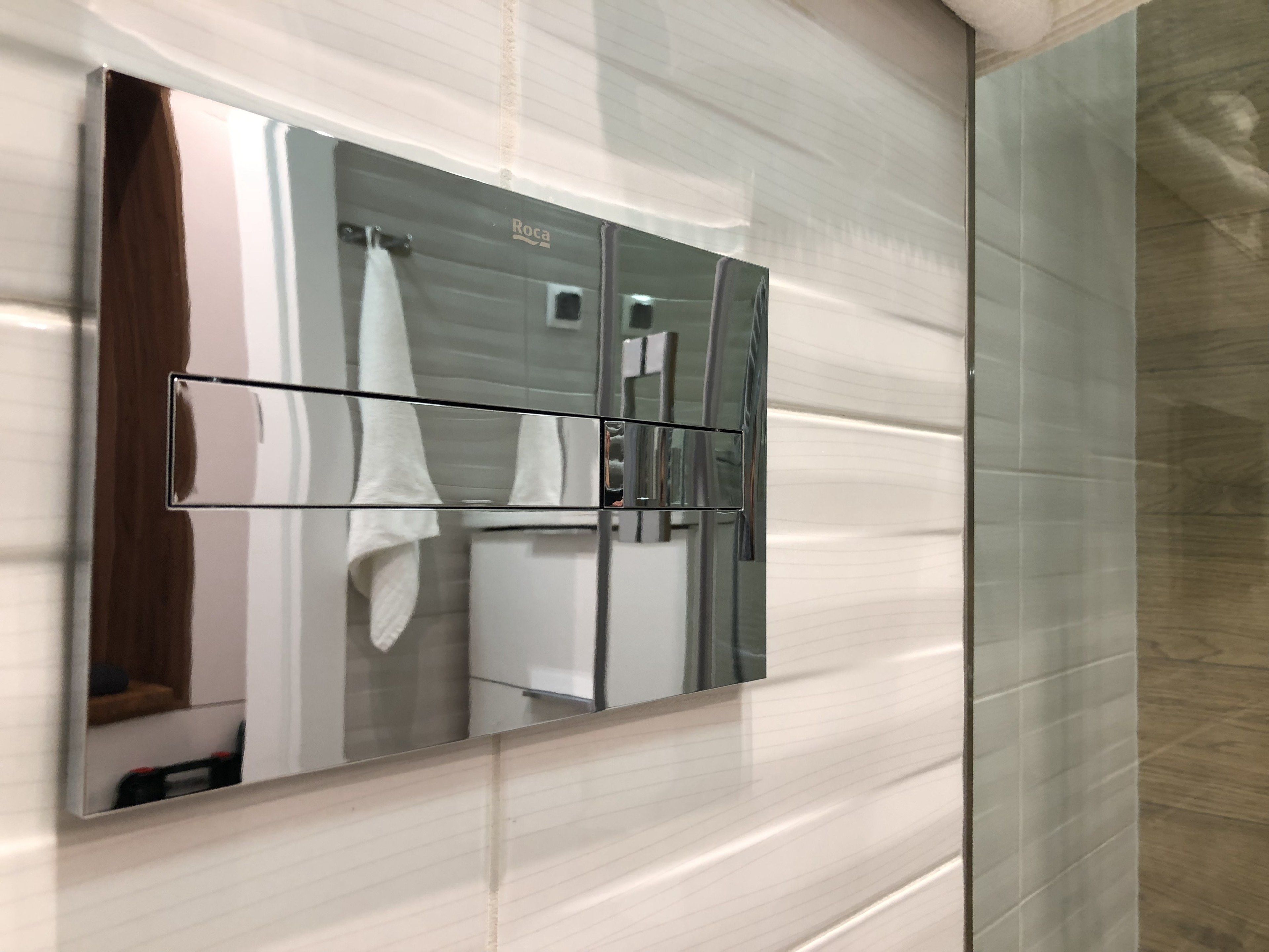 Une salle de bain avec un grand miroir, un porte-serviettes et une paroi en verre.