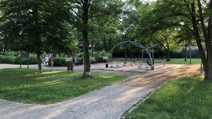 A park with a paved walkway, exercise equipment, and benches. - Like at Home Warsaw (Warsaw)
