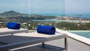 A balcony with two blue towels and a view of a coastal landscape. - Villa Victoria (Koh Samui)