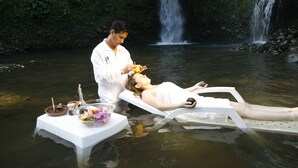 A person lying on a floating platform in a natural setting with a waterfall in the background. - Kashama Eco Resort y Spa (Valle Hermoso)