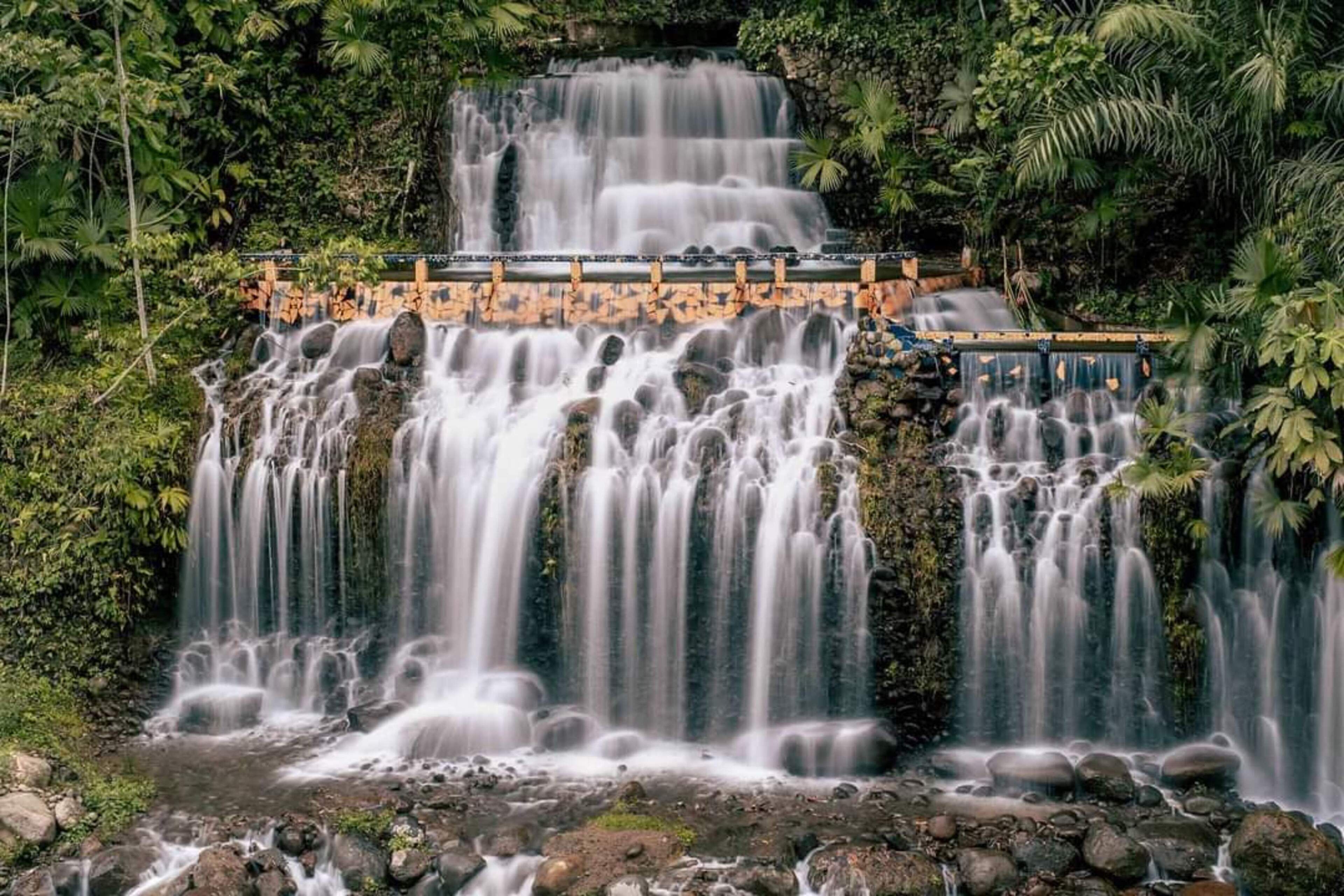 A multi-tiered waterfall with a wooden viewing platform.