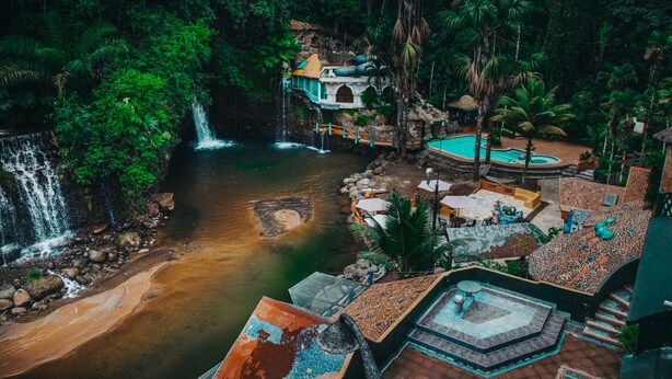 A resort with a waterfall, a pool, and a terraced area with outdoor seating. - Kashama Eco Resort y Spa (Valle Hermoso)