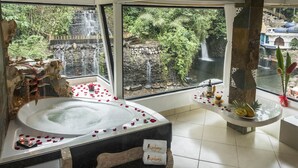 A bathroom with a large bathtub, a view of a waterfall, and a stone wall. - Kashama Eco Resort y Spa (Valle Hermoso)