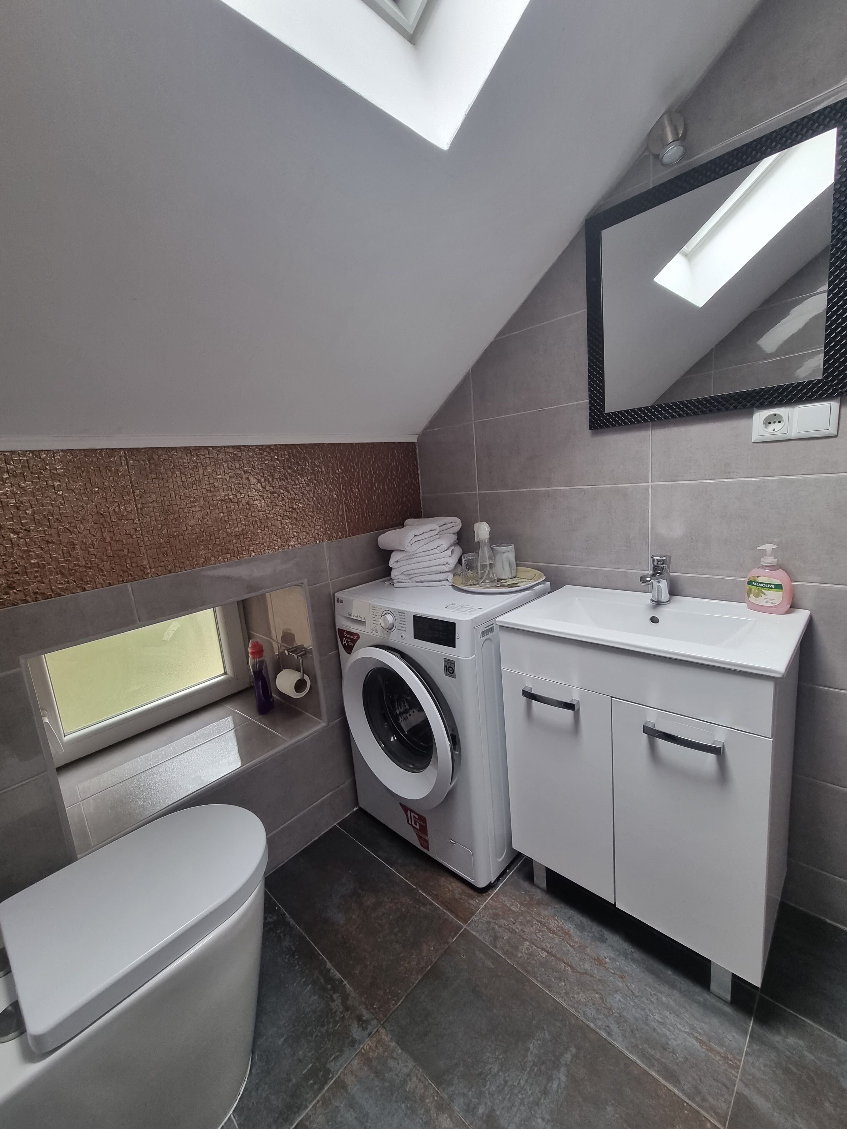 Un baño pequeño con lavadora, inodoro y lavamanos.