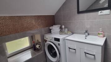 Un baño pequeño con lavadora, inodoro y lavamanos.