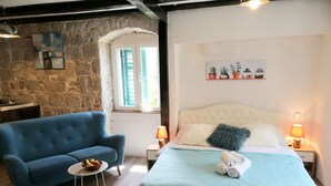 A bedroom with a bed, a blue armchair, a small round table with fruits, and a fluffy rug. - Apartment Trumbic (Split)