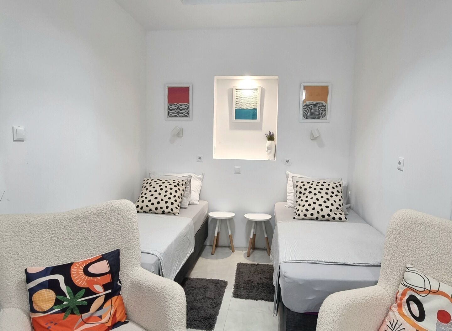 Una habitación pequeña y moderna con dos camas individuales, una mesita y un sofá.