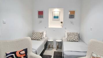 Una habitación pequeña y moderna con dos camas individuales, una mesita y un sofá.