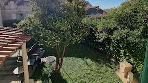 A courtyard with a tree, a bench, and a car parked in the background. - Apartment Trumbic (Split)