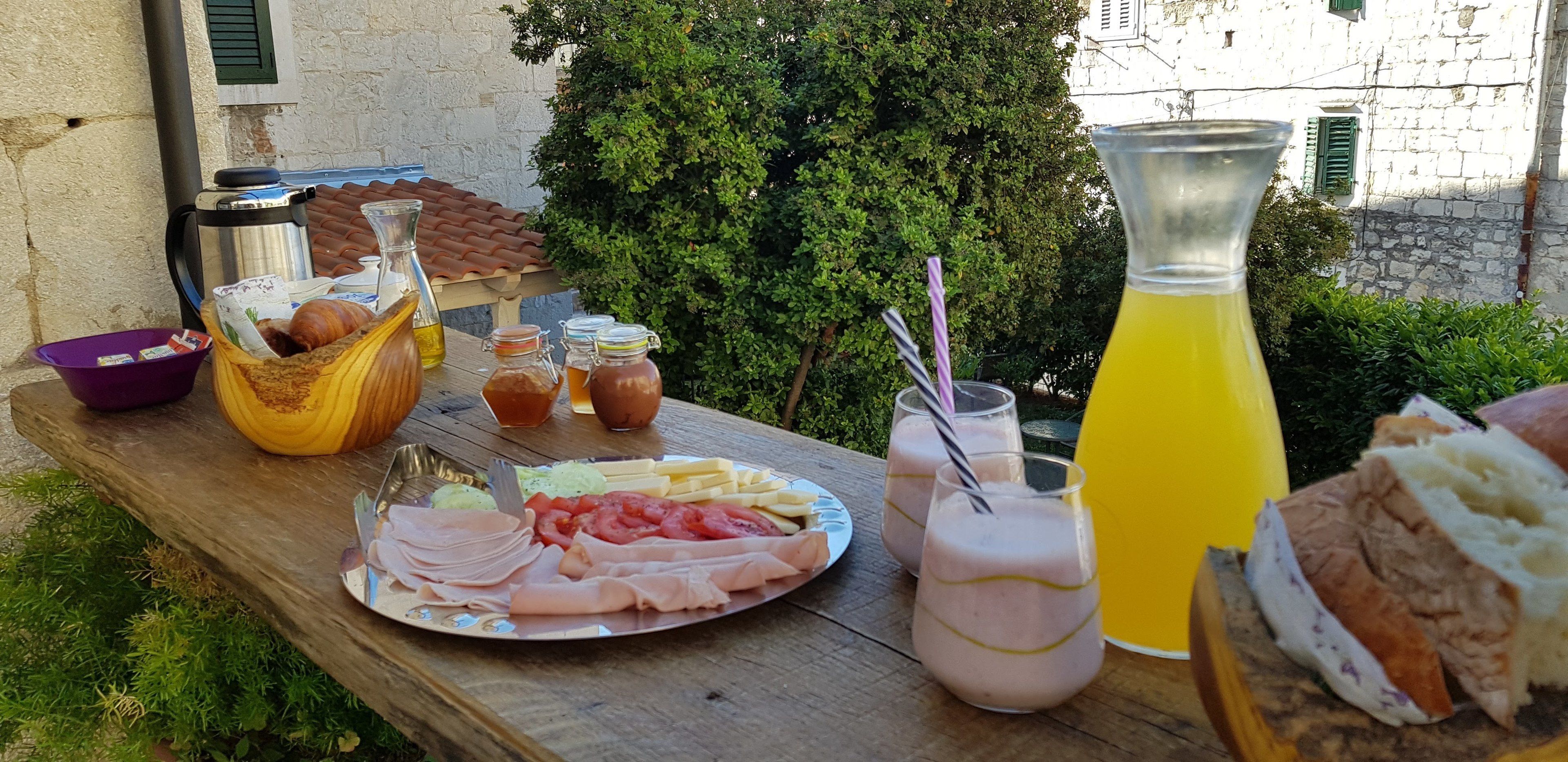 Un montaje para picnic con comida y bebidas sobre una mesa de madera al aire libre.