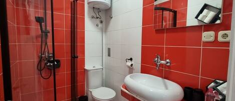A bathroom with a shower, toilet, and sink, featuring red and white tiles.