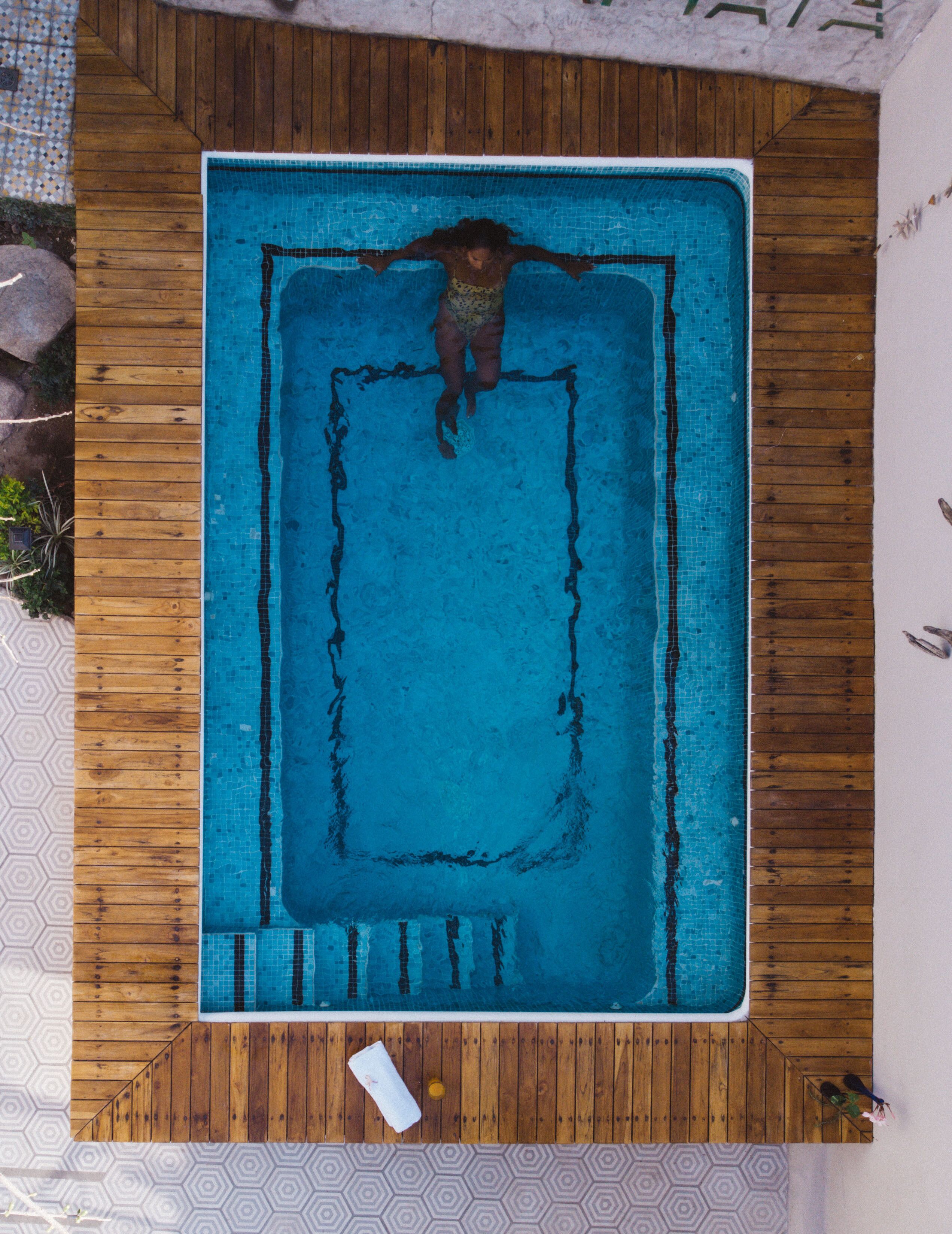 An aerial view of a rectangular swimming pool with wooden decking surrounding it.