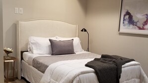Une chambre à coucher avec un lit, une table de chevet, une lampe et un tableau au mur.