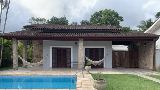 Ein Haus mit Schwimmbad, steinernen Säulen und einer überdachten Terrasse.