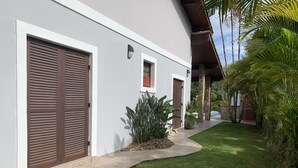 Ein modernes Haus mit zwei großen braunen Türen, einem kleinen Fenster und einem gepflegten Rasen.