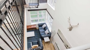 Et moderne interiør med en sort lædersofa, et lille bord og et dekorativt gevir på væggen.
