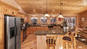 A modern kitchen with wooden cabinets, stainless steel appliances, and a granite countertop. - Mountain Bliss by Destination Big Bear : Remarkable Single Story Log Style Home in Pinewood Estates! Outdoor Hot Tub! Arcade! (Big Bear City)