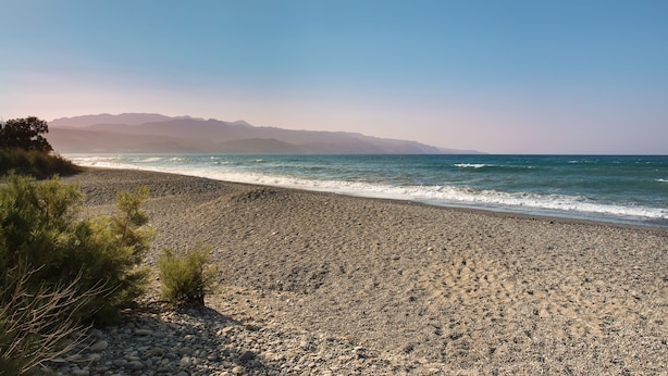 A rocky beach with a clear view of the ocean and distant mountains. - Sirens House (Platanias)