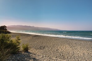 Una playa rocosa con una vista despejada del océano y montañas lejanas.
