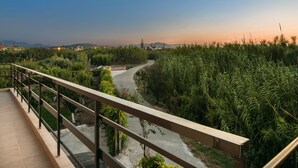 A balcony with a view of a river, surrounded by greenery and a clear sky. - Sirens House (Platanias)
