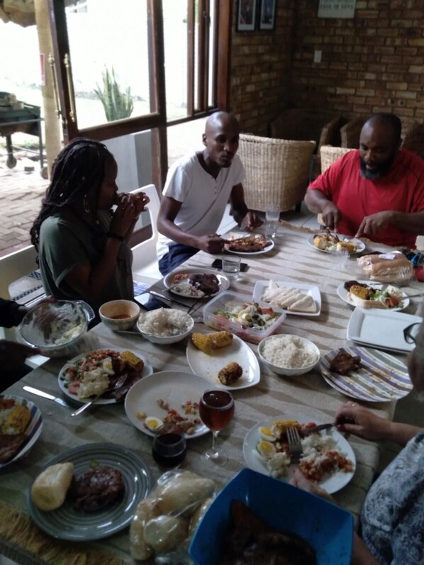 Un grupo de personas comiendo en una mesa, con varios platos que incluyen arroz, pan y carne.
