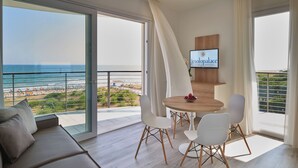 Ein modernes Wohnzimmer mit großem Balkon, einem Holzessttisch mit Stühlen und einem an der Wand montierten Fernseher.