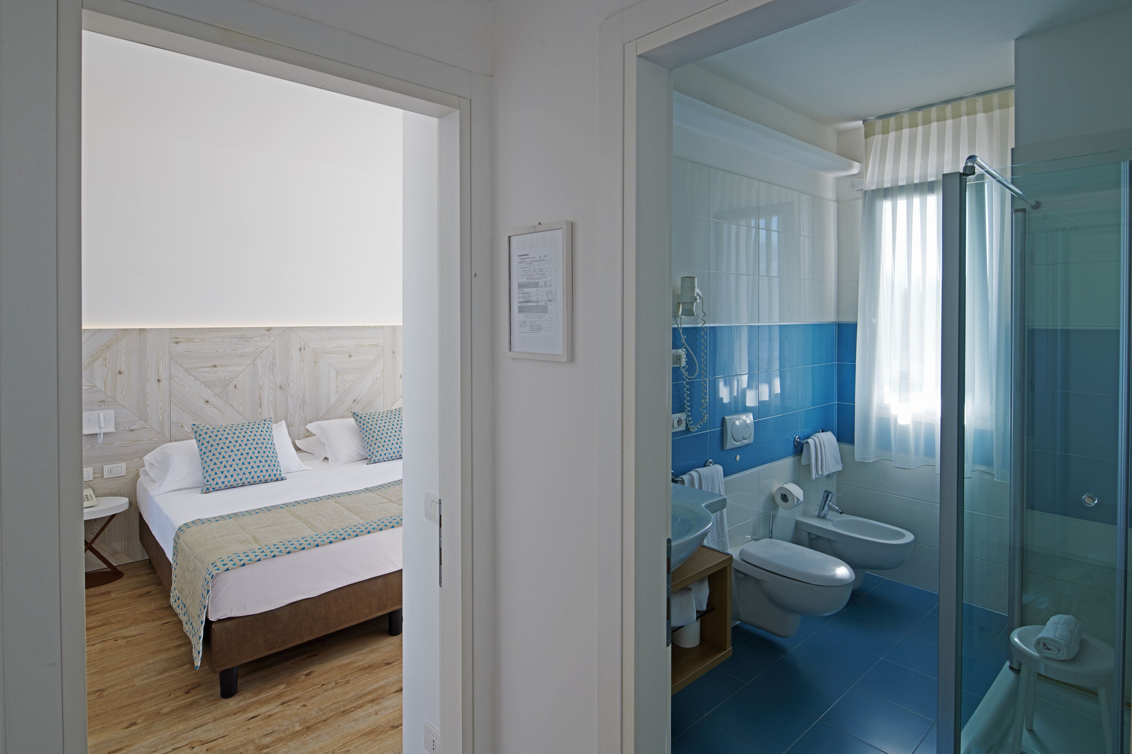 A bedroom with a bed, a bedside table, and a nightstand. The bathroom includes a toilet, a sink, a shower, and a bathtub.