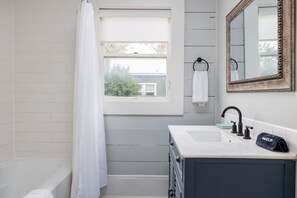 Een bad/douchecombinatie, een haardroger, handdoeken, zeep