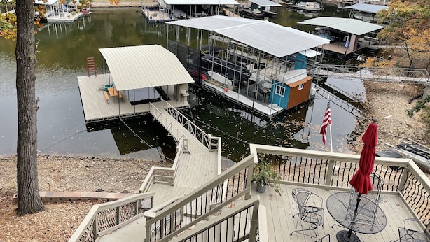 A waterfront property with multiple docked boats, a covered deck area, and a staircase leading to a deck with outdoor seating. - Great Location!  Heart of Horseshoe Bend-2MM in Lake of the Ozarks. (Lake Ozark)