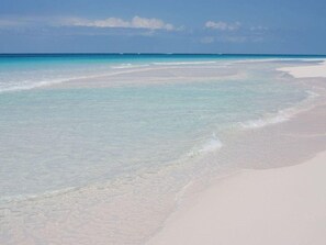 Ein Strand mit klarem türkisblauem Wasser und weißem Sand.